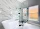 Elegant bathroom with soaking tub, glass shower, and marble tile at 133 Andalusia Loop, Davenport, FL 33837