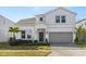 Two-story house with a light-colored facade, a gray garage door, and landscaping at 3525 Lavender Dr, Davenport, FL 33897