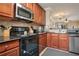 View of kitchen with black appliances and wood cabinetry at 901 Charo Pkwy # 721, Davenport, FL 33897