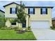 Two-story yellow house with a white garage door and landscaping at 4406 Trotters Way, Lakeland, FL 33801