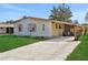 Single-wide mobile home with carport and lush green lawn at 450 Tivoli Park Dr, Davenport, FL 33897