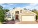 Tan house with a two-car garage and mature landscaping at 223 Lake Davenport Estates, Davenport, FL 33897