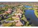 An aerial view of a neighborhood with tile roofs, surrounded by lush greenery and a tranquil lake at 513 Viterra Ct, Kissimmee, FL 34759