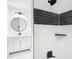 Updated bathroom with white vanity, black and white tile shower, and round mirror at 117 W Maple St, Davenport, FL 33837