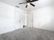 Well-lit bedroom with ceiling fan, carpet, and access to hallway at 117 W Maple St, Davenport, FL 33837