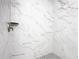 Clean shower with marble-style tile and grey hexagon floor tile at 117 W Maple St, Davenport, FL 33837