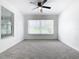 Bedroom with ceiling fan, grey carpet, and a large window overlooking the outdoors at 117 W Maple St, Davenport, FL 33837