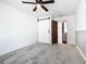 Bedroom with ceiling fan, grey carpet, barn door, and access to another room at 117 W Maple St, Davenport, FL 33837