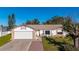 White house with brick accents, a two-car garage, and a landscaped yard at 1402 Westminster Way, Kissimmee, FL 34744