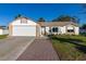 White house with brick accents, a two-car garage, and a landscaped yard at 1402 Westminster Way, Kissimmee, FL 34744