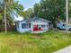 1920s bungalow with red door and overgrown yard at 1015 Ohio Ave, Saint Cloud, FL 34769