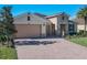 House exterior showcasing a tan-colored home with a two-car garage and stone accents at 678 Irvine Ranch Rd, Kissimmee, FL 34759