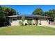 Tan brick home with solar panels, lush lawn, and mature trees at 112 10Th St, St Cloud, FL 34769