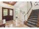 Elegant entryway with double doors, tile flooring, and a staircase with patterned carpet at 7435 Gathering Ct, Reunion, FL 34747