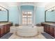 Elegant bathroom with a large free-standing tub, and vanities, and neutral tile floors at 7435 Gathering Ct, Reunion, FL 34747