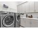 Bright laundry room with gray cabinets, washer, and dryer at 2692 Meadowedge Loop, St Cloud, FL 34772