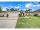 Two-car garage, light beige exterior, and landscaped front yard at 3838 Gulf Shore Cir, Kissimmee, FL 34746