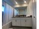 Bathroom with double vanity, white cabinets, and a bathtub shower combo at 4295 Paragraph Dr, Kissimmee, FL 34746