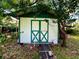 White and green shed with ramp access in a tree-shaded yard at 5312 Goddard Ave, Orlando, FL 32810