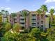 Attractive condo building with lush landscaping and palm trees at 7662 Whisper Way # 402, Reunion, FL 34747