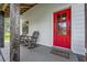 Red front door entrance with rocking chairs on porch at 965 Keen Rd, Frostproof, FL 33843