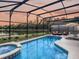 Gorgeous screened pool and spa at sunset with lake views at 973 Lake Berkley Dr, Kissimmee, FL 34746