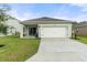 House exterior showcasing a two-car garage and covered patio at 6883 Botanic Blvd, Harmony, FL 34773