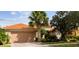 Tan house with terracotta roof, two-car garage, and lush landscaping at 561 Sienna Dr, Poinciana, FL 34759
