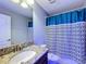 Bathroom with granite countertop, teal shower curtain, and updated fixtures at 9158 Wedge Dr, Davenport, FL 33896