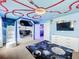 Themed bedroom with bunk beds, featuring a space-themed mural and ceiling design, and a view into a nearby theater room at 9158 Wedge Dr, Davenport, FL 33896