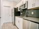 Galley kitchen with stainless steel appliances and dark tile backsplash at 2971 Camden Way, Davenport, FL 33837