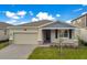 One-story home with light beige siding, gray roof, and landscaped yard at 2971 Camden Way, Davenport, FL 33837