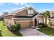 Two-story house with a brown exterior, two-car garage, and palm tree at 131 Cadiz Loop, Davenport, FL 33837