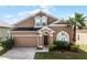 Two-story house with a brown exterior, two-car garage and palm tree at 131 Cadiz Loop, Davenport, FL 33837