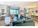 Spacious living room with a teal sectional sofa, large sliding glass doors, and a view of the water at 445 Via Abruzzi St, Poinciana, FL 34759
