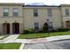Front view of a two-story townhouse with a burgundy door and landscaping at 2846 Club Cortile Cir, Kissimmee, FL 34746