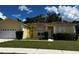 Single-story house with attached garage, landscaping, and a yellow exterior at 481 Peppermill Cir, Kissimmee, FL 34758