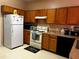 Galley kitchen with wood cabinets, white appliances, and tile floor at 481 Peppermill Cir, Kissimmee, FL 34758