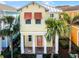 Two-story yellow house with orange accents and a metal roof, surrounded by palm trees at 3075 Key Lime Loop, Kissimmee, FL 34747