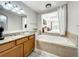 Bathroom with granite countertop, wooden cabinets, and a garden tub at 7510 Seven Eagles Way # 7510, Reunion, FL 34747