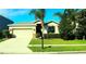 Tan house with a white garage door, landscaping, and palm trees at 1569 Thetford Cir, Orlando, FL 32824