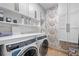 Bright laundry room with modern washer and dryer, stylish cabinetry, and decorative wallpaper at 729 Main Street, Windermere, FL 34786