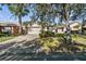 Landscaped front yard with brick paver driveway and mature trees at 200 Grand Canal Dr, Kissimmee, FL 34759