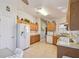 Galley kitchen with oak cabinets, white appliances, and tile floor at 200 Grand Canal Dr, Kissimmee, FL 34759