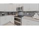 Modern kitchen with stainless steel appliances and gray tile backsplash at 3000 Penelope Loop, Kissimmee, FL 34746