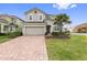 Two-story house with a gray exterior, two-car garage, and a brick paved driveway at 4449 Shiva Loop, Kissimmee, FL 34746