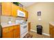 Galley kitchen with wood cabinets, white appliances, and tile floors at 2302 Butterfly Palm Way # 303, Kissimmee, FL 34747
