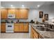 Modern kitchen with wood cabinets, granite counters, and white appliances at 9051 Treasure Trove Ln # 207, Kissimmee, FL 34747