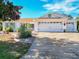 White house with brown roof, two-car garage, and nicely landscaped yard at 2494 Five Forks Trl, The Villages, FL 32162