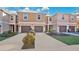 Tan three-story townhouses with brown garages, landscaping, and a paved driveway at 1336 Chelsea Dr, Davenport, FL 33897